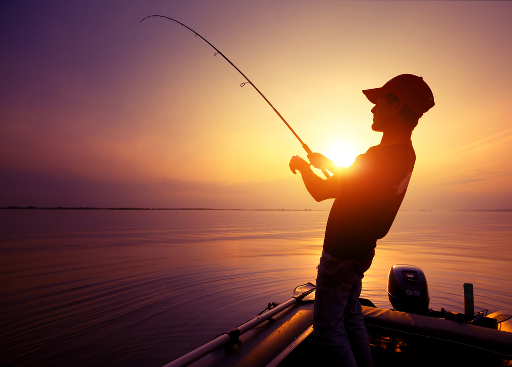 Young,Man,Fishing,On,Wide,River,From,The,Boat,At
